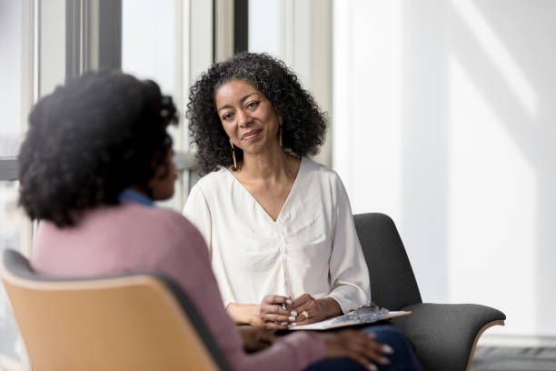 The mature adult female therapist listens compassionately to the unrecognizable female client share her problems.